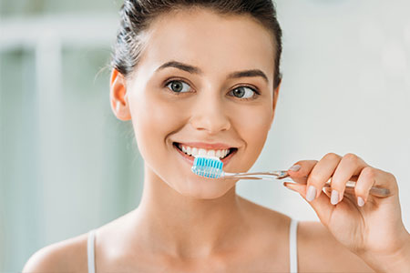 Woman with beautiful smile brushing her teeth